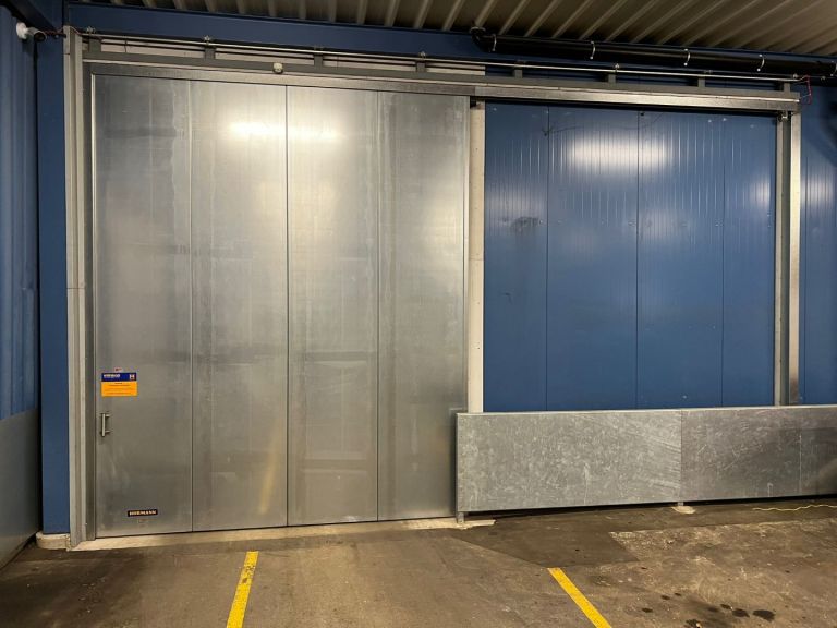 Industrie-Sektionaltor APU F42 mit Schlupftüre und geschlossenem Feuerschutzschiebetor FST 1